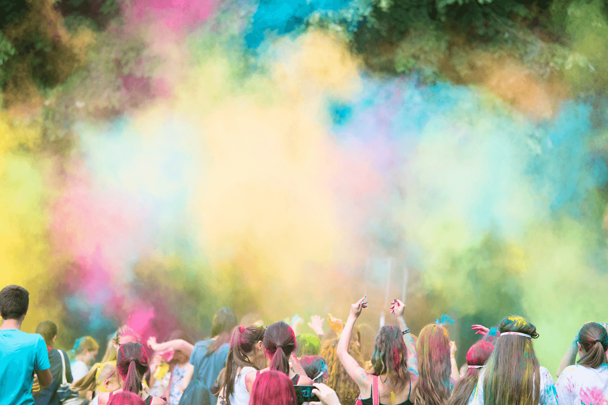 A group of multicultural people throw coloured powder in the air as they celebrate the Indian festival of Holi. 