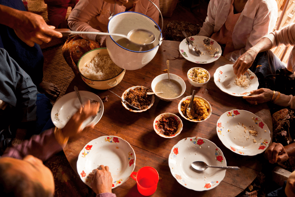 A table laid out Asian-style with the main dishes at the center of the table, as people serve themselves on their own plates. 